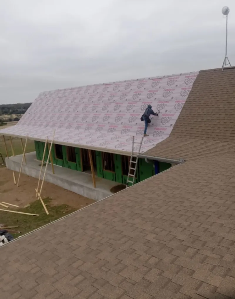 Worker preparing underlayment for a metal roof installation in Ashland